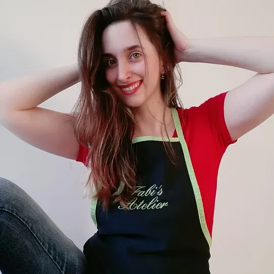 Fabiana de avental do atelier, com as mãos no cabelo