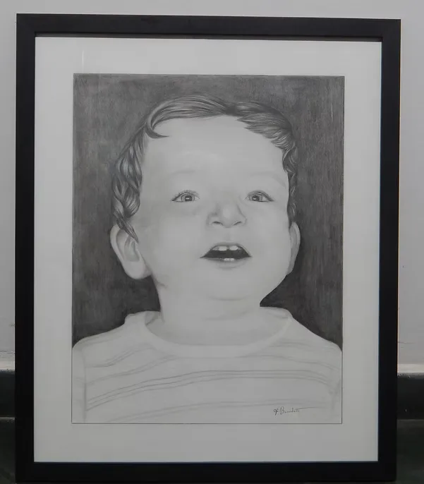 Retrato a grafite de uma criança sorrindo, emoldurado